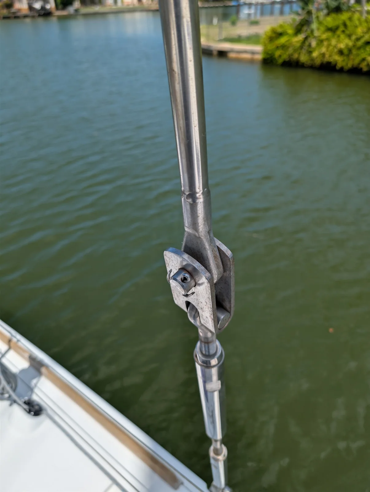 Stainless sailboat standing-rigging terminal and toggle above the deck edge.